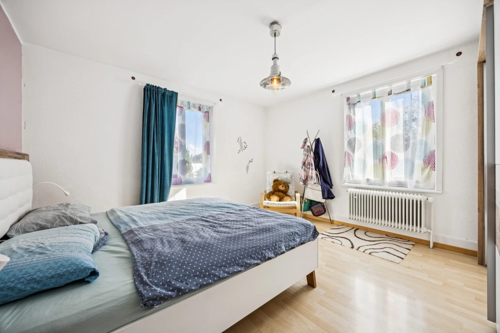 room featuring light wood-style floors, radiator, and decorative light fixtures
