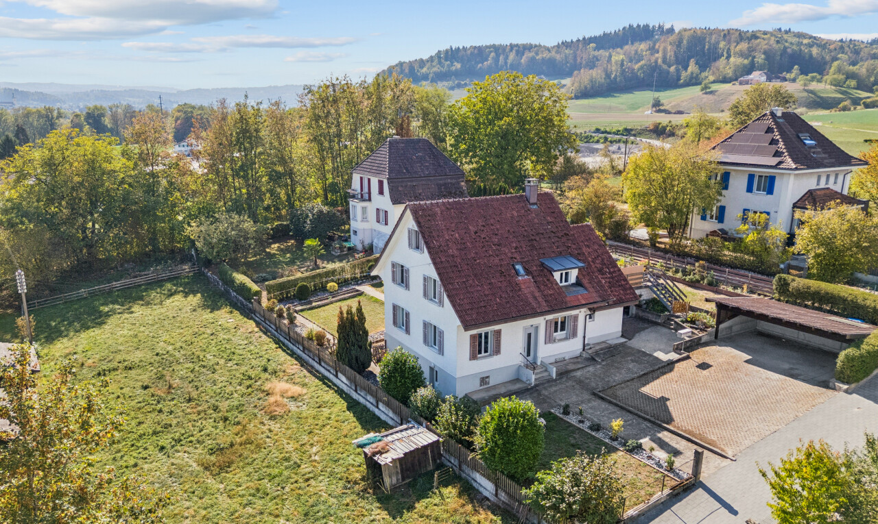 view of property featuring a garage, a fenced backyard, driveway, and a chimney