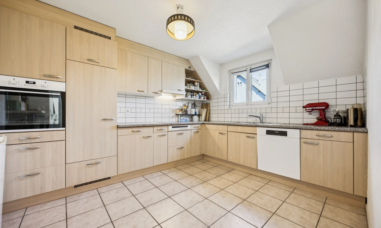 cuisine avec armoires marron clair, light brown cabinets, light floor, four, et lave-vaisselle