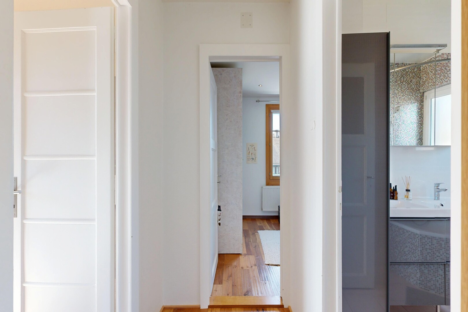 couloir avec cloison sèche, drywall, sol en finition bois, wood finish floor, et lumière naturelle