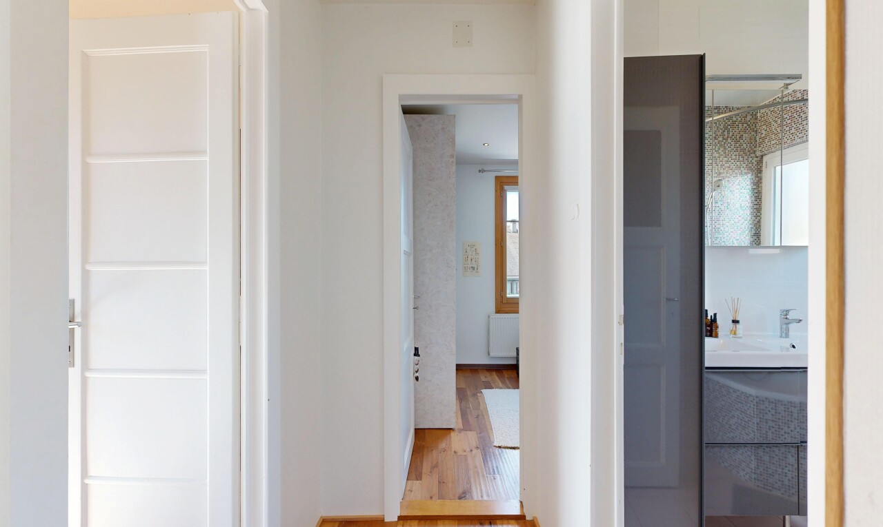 couloir avec cloison sèche, drywall, sol en finition bois, wood finish floor, et lumière naturelle