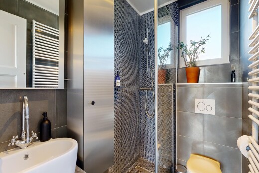 full bath with a towel warmer, a stall shower, radiator, and tile walls