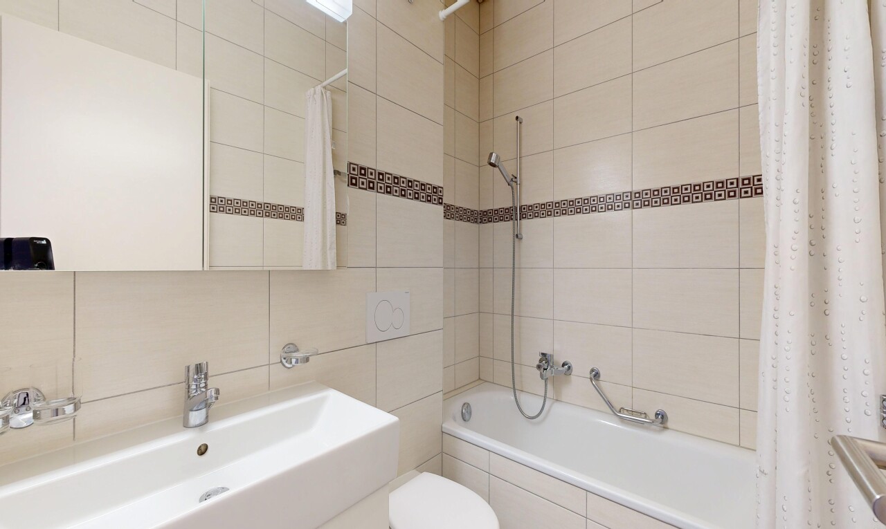 full bath with tile walls, tiled shower / bath, and vanity