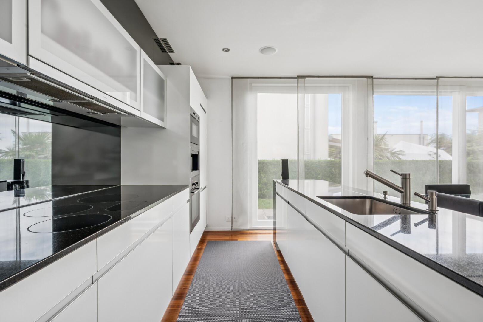 kitchen with white cabinets, dark wood-style floors, dark stone countertops, stainless steel oven, and glass insert cabinets