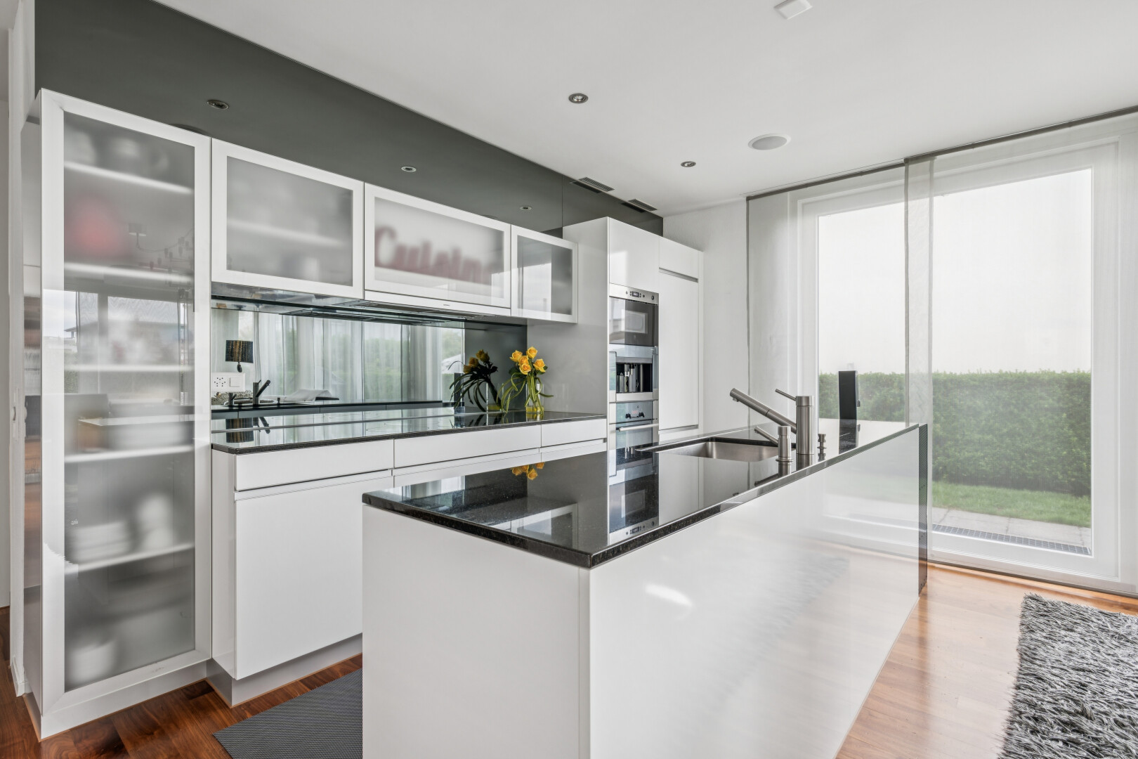 kitchen featuring glass fronted cabinets, white cabinetry, dark wood-type flooring, a kitchen island with sink, and stainless steel appliances