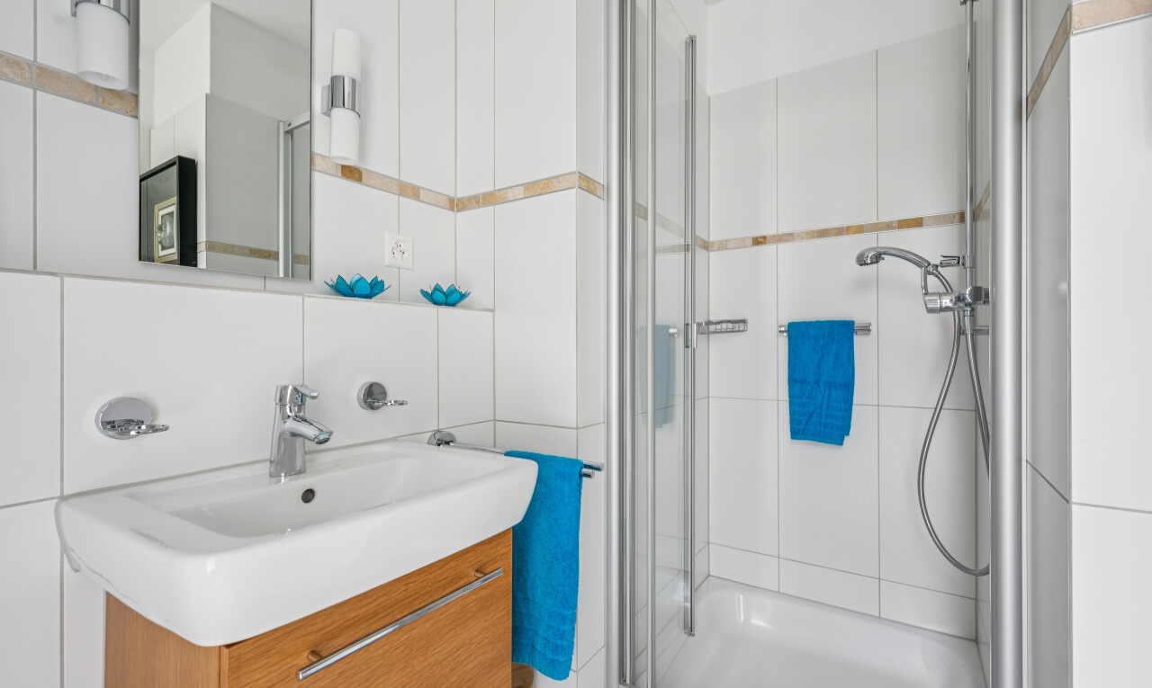full bath featuring a stall shower, vanity, and tile walls