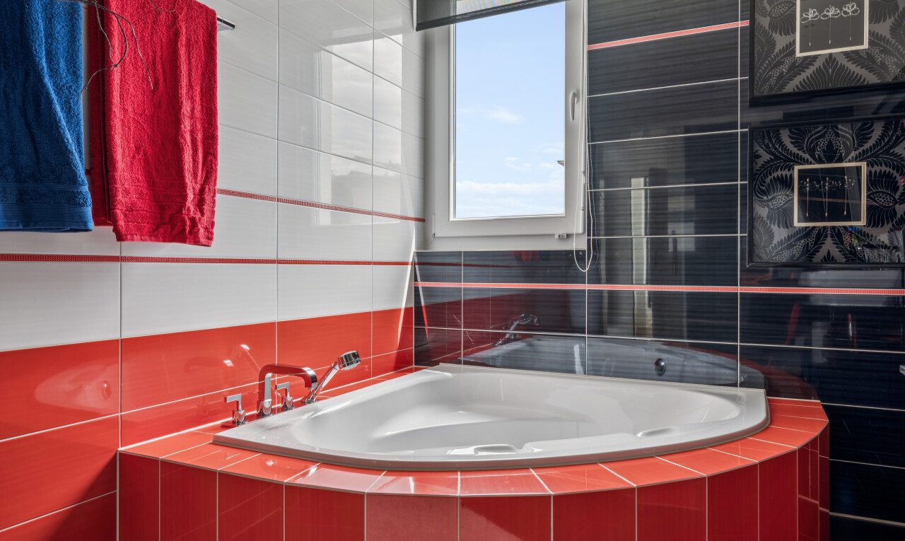bathroom featuring tile walls, tiled tub, and a shower