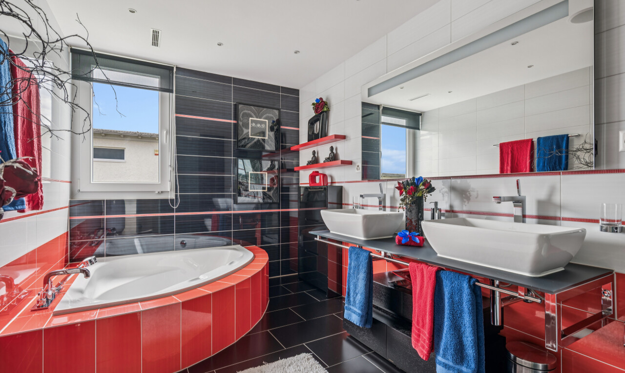 full bathroom featuring tile walls, a bath, double vanity, and dark tile patterned floors