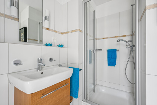 full bath featuring a stall shower, vanity, and tile walls