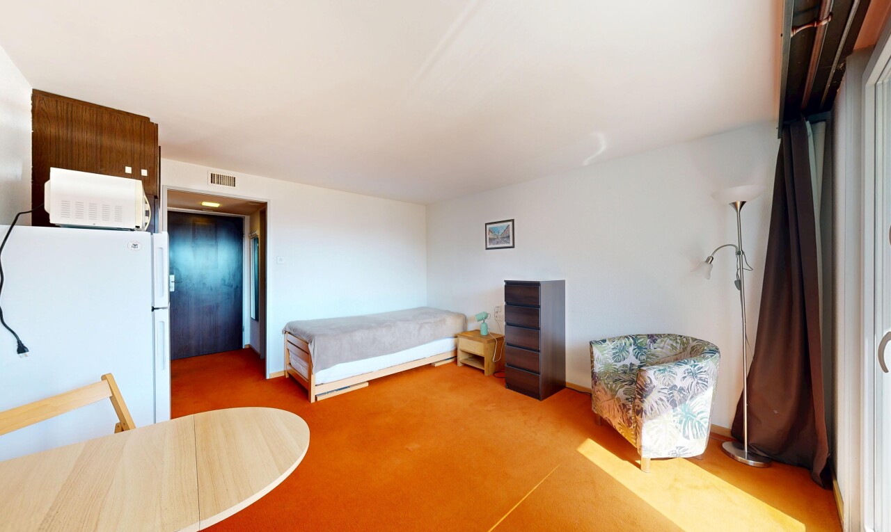 room with freestanding refrigerator and light colored carpet