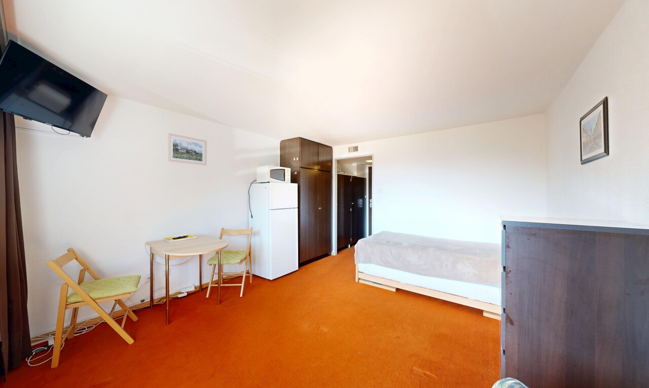 room / bedroom featuring freestanding refrigerator and light carpet