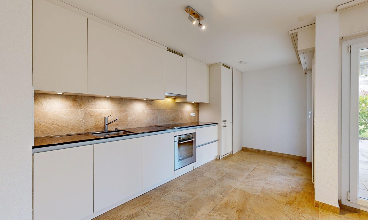 cuisine avec armoires à panneau plat, plans de travail, drywall, cloison sèche, et backsplash