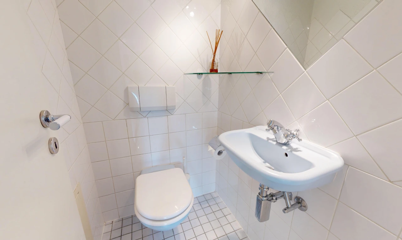 salle de bains avec toilette, mur en carrelage, tile wall, évier, et sol en carrelage