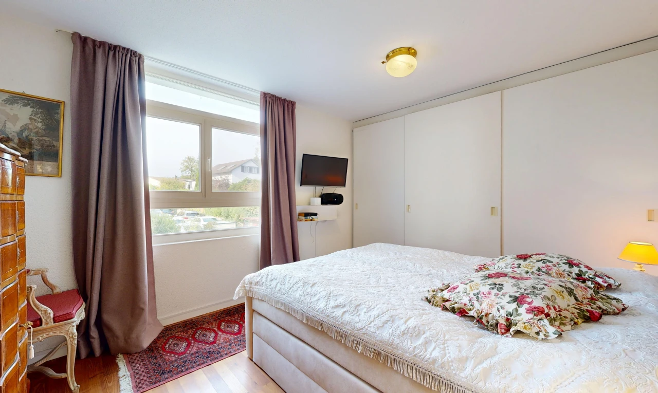 chambre avec placard, télévision, wood finish floor, sol en finition bois, et drywall