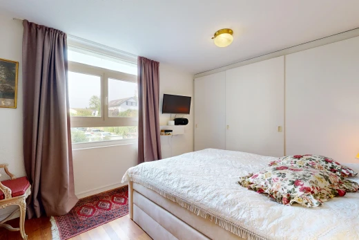 zimmer / schlafzimmer mit kleiderschrank, fernseher, wood finish floor, holzfußboden, und drywall