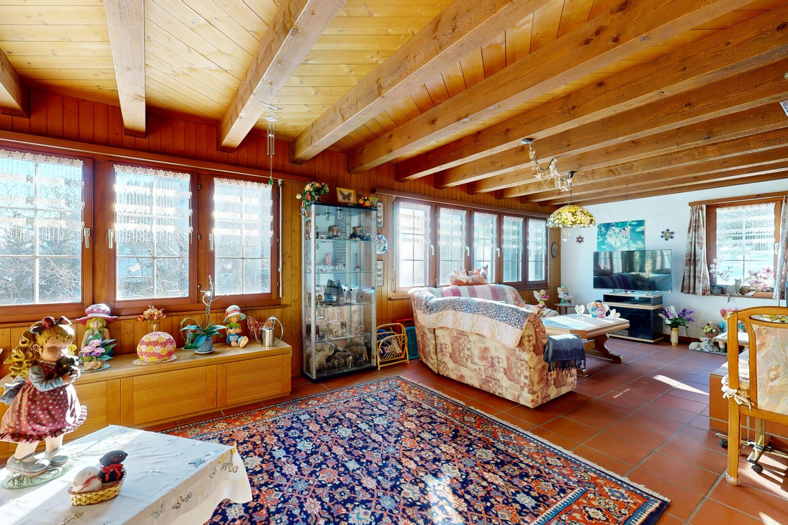 salon avec inside property, télévision, natural light, lumière naturelle, et wood ceiling