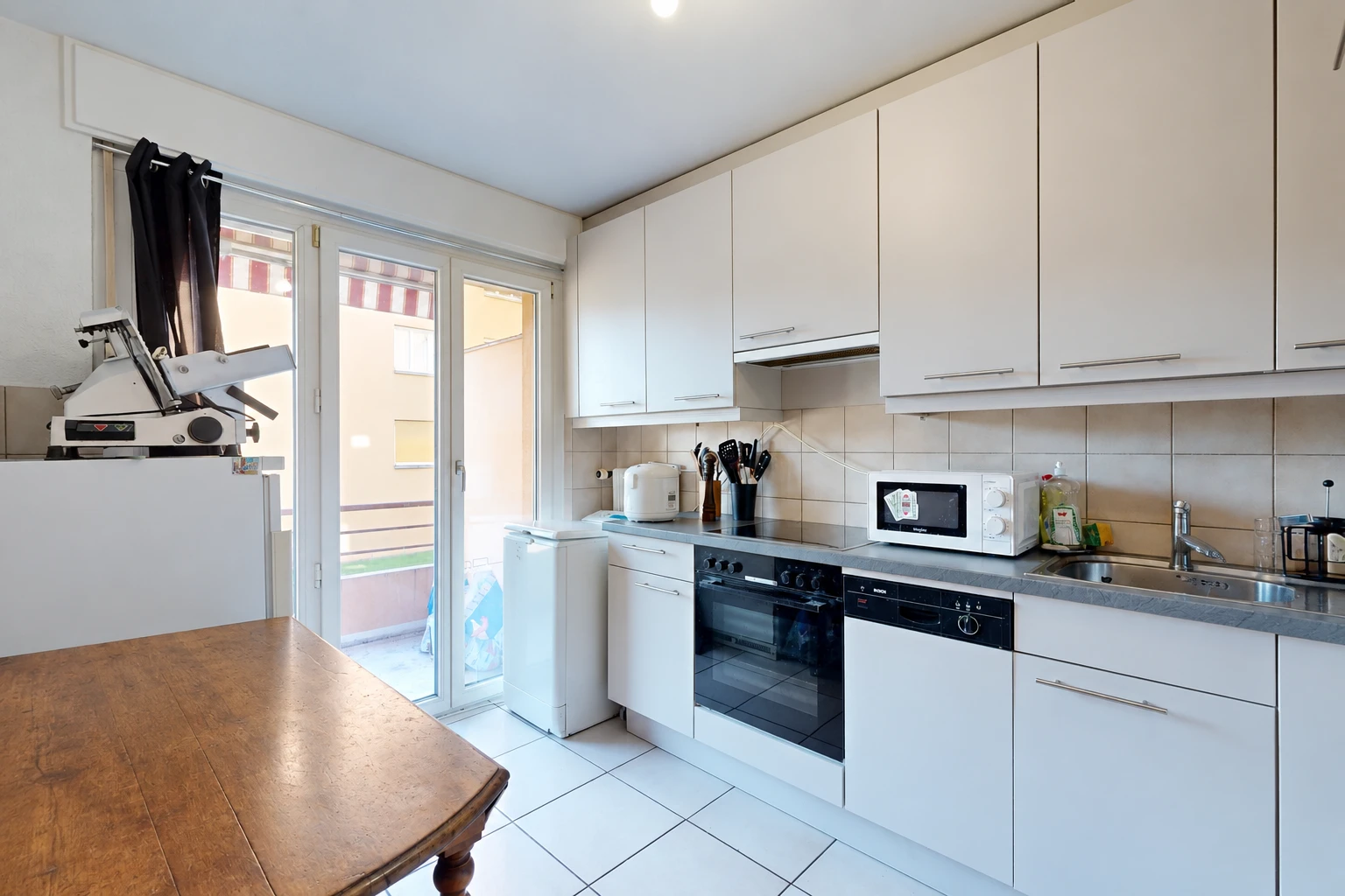 cuisine avec four, light floor, accès à l'extérieur, armoires blanches, et white cabinets