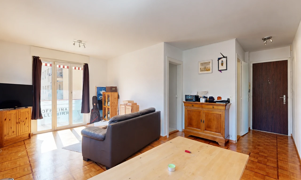 salon avec télévision, cloison sèche, drywall, accès à l'extérieur, et sol en finition bois