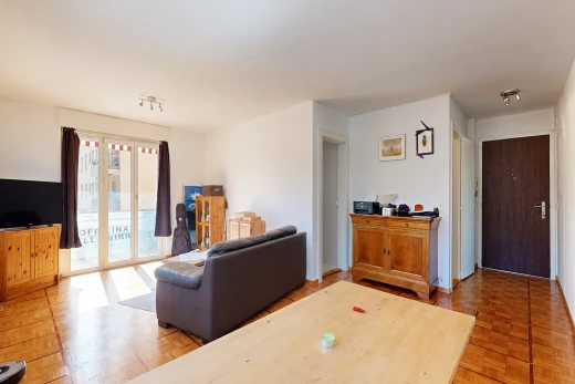 salon avec télévision, cloison sèche, drywall, accès à l'extérieur, et sol en finition bois