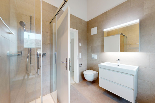 salle de bains avec mur carrelé, toilettes, meuble-lavabo, miroir, et douche