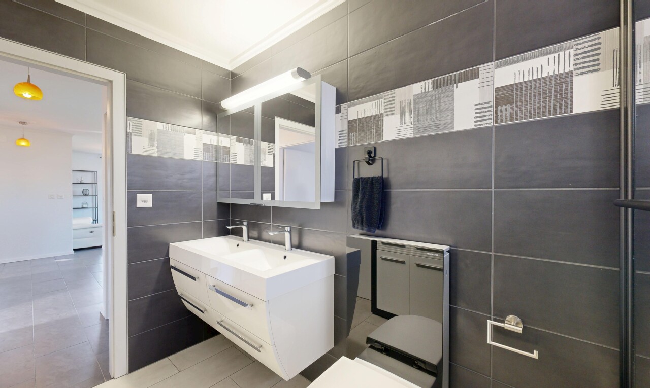 salle de bains avec mur en carrelage, tile wall, miroir, lavabo (ou coiffeuse selon le contexte), et light floor