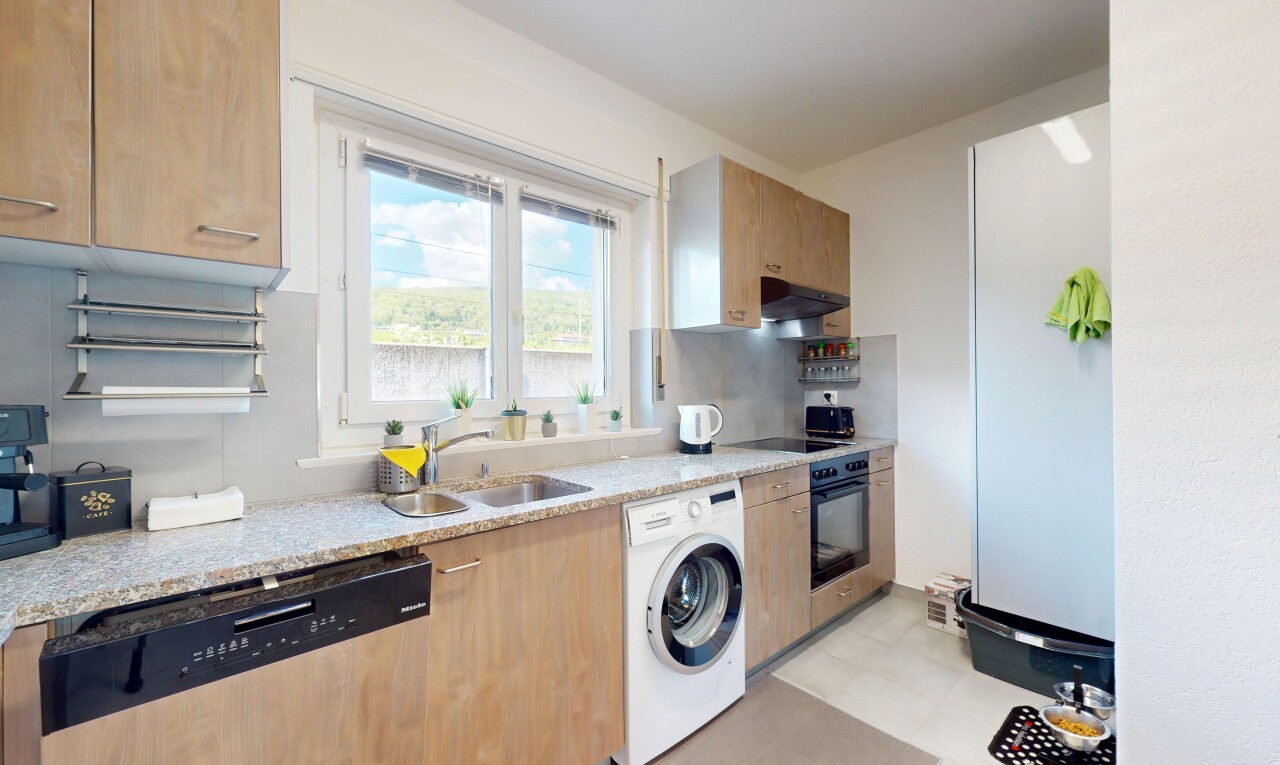 kitchen with a sink, light countertops, washer / clothes dryer, under cabinet range hood, and black appliances