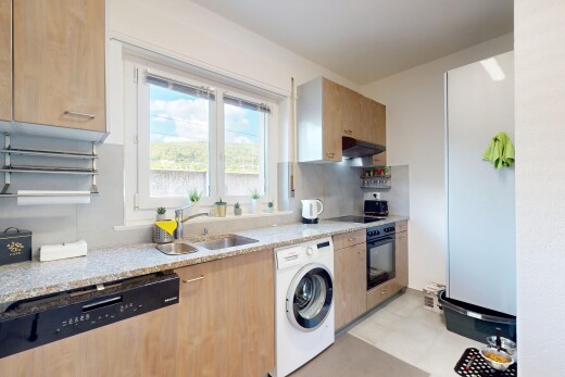 kitchen with a sink, light countertops, washer / clothes dryer, under cabinet range hood, and black appliances
