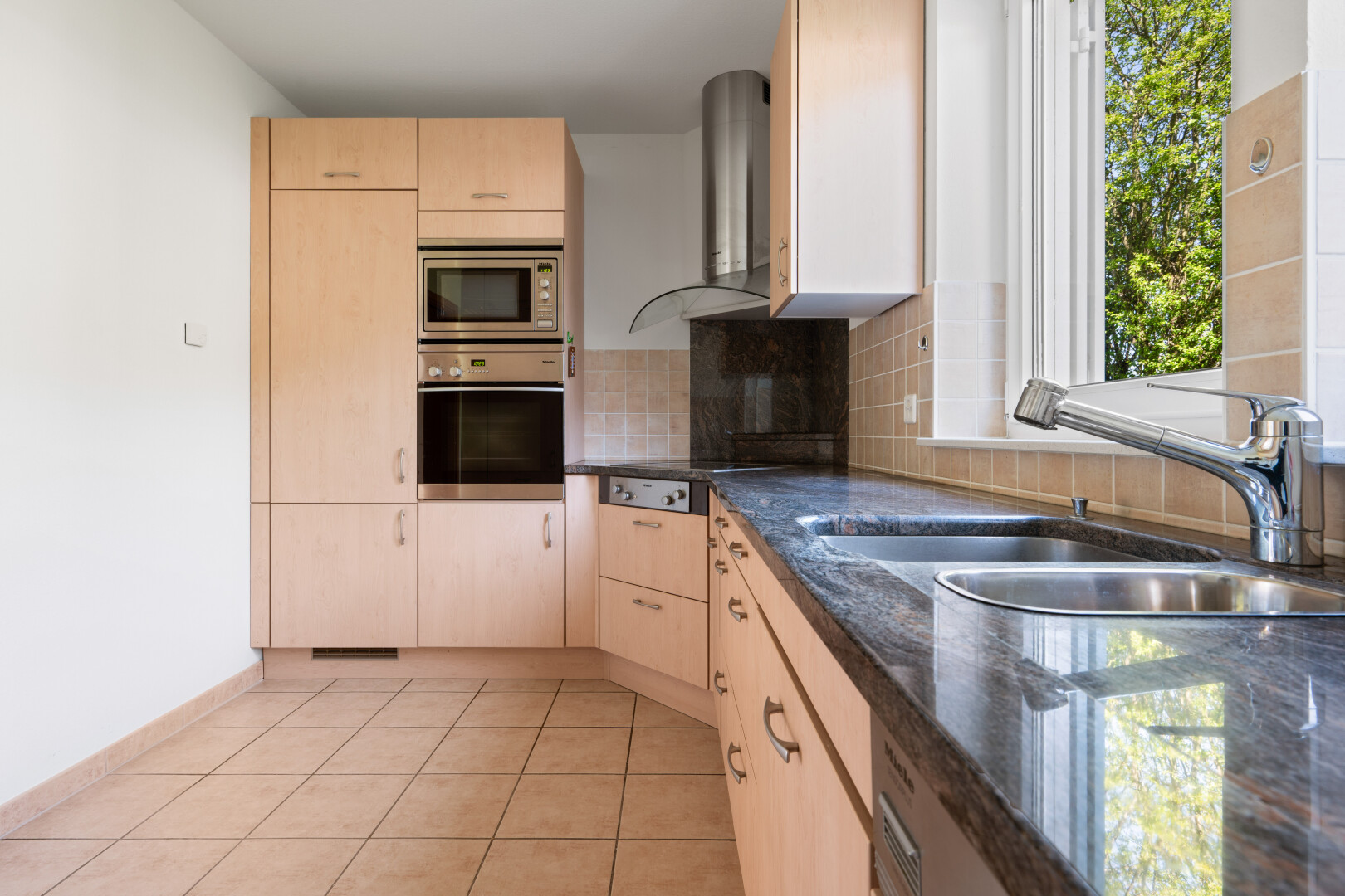 küche mit dark countertops, light floor, hellbraune schränke, light brown cabinets, und ofen