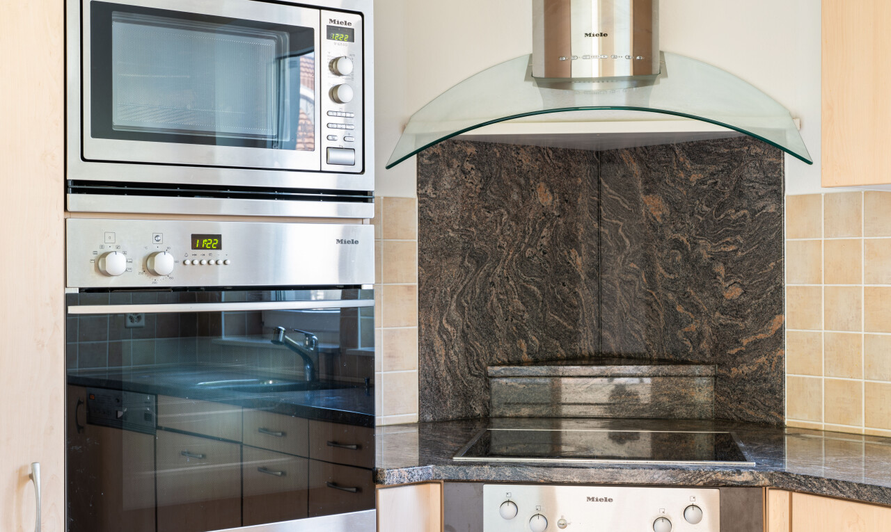 cuisine avec hotte, four, dark countertops, micro-ondes, et inside property