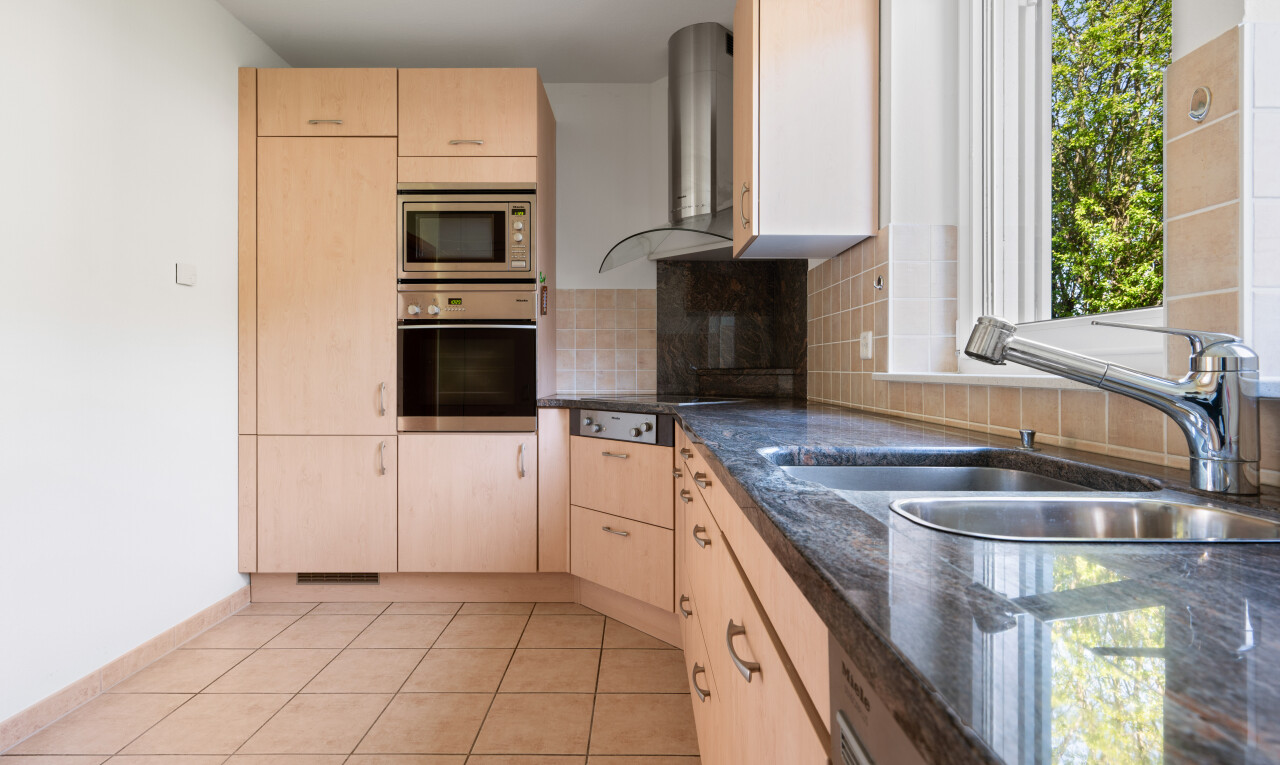 küche mit dark countertops, light floor, hellbraune schränke, light brown cabinets, und ofen