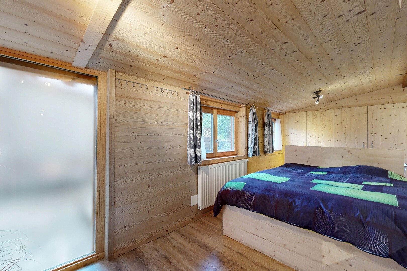 chambre avec wood finish floor, sol en finition bois, wood wall, mur en bois, et inside property