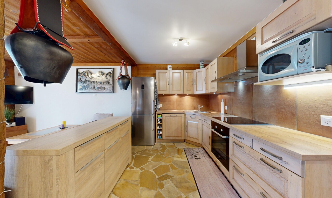 cuisine avec plans de travail en bois de boucher, micro-ondes, hotte, réfrigérateur, et stone finish floor