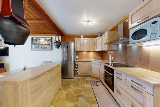 cuisine avec plans de travail en bois de boucher, micro-ondes, hotte, réfrigérateur, et stone finish floor