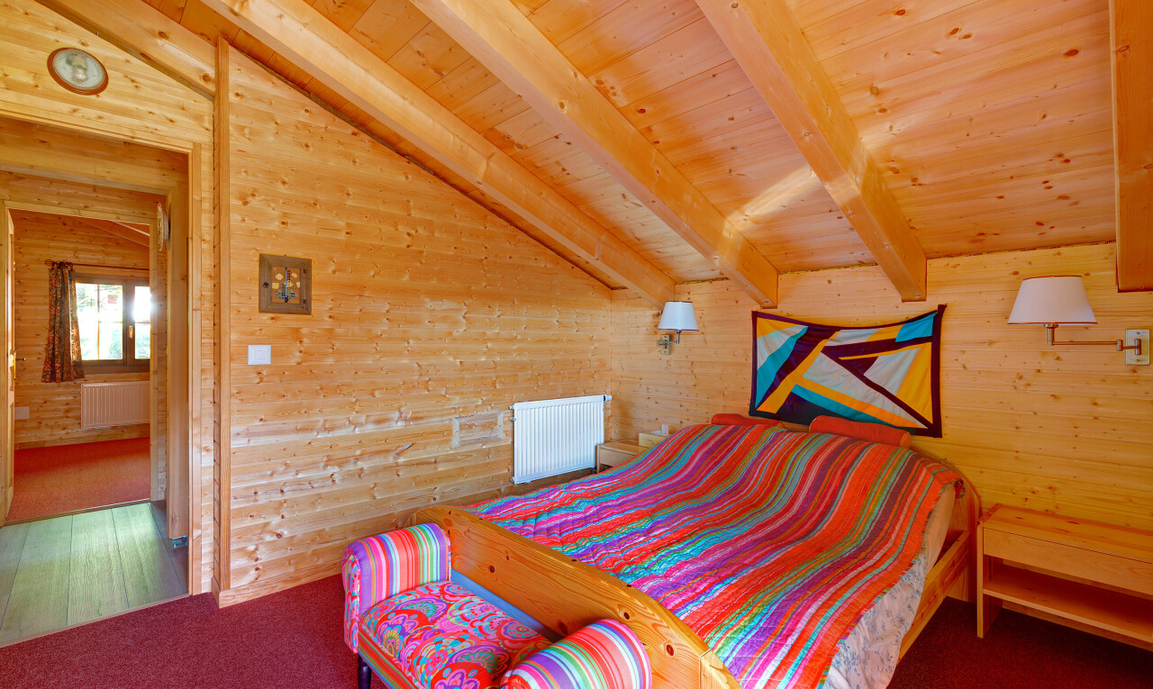 chambre avec vaulted ceiling, plafond voûté, wood wall, mur en bois, et beamed ceiling