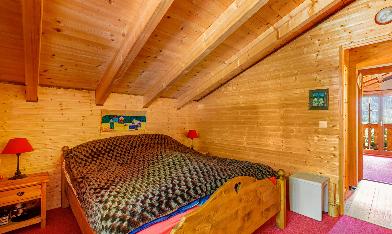 chambre avec inside property, mur en bois, wood wall, plafond à poutres, et beamed ceiling