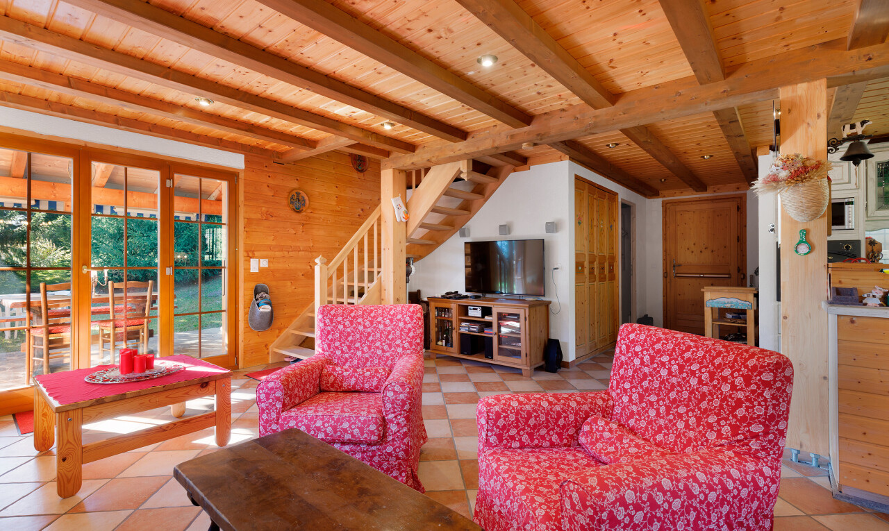 salon avec beamed ceiling, plafond à poutres, wood wall, mur en bois, et escaliers
