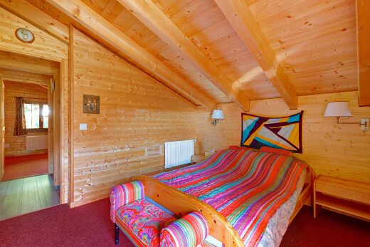 chambre avec vaulted ceiling, plafond voûté, wood wall, mur en bois, et beamed ceiling