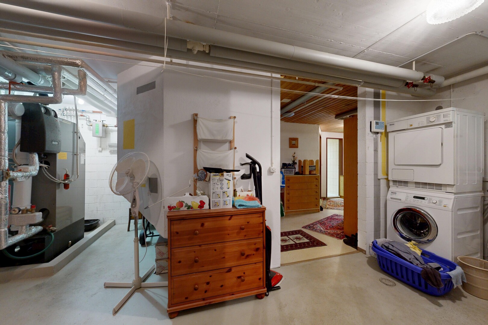 buanderie avec concrete floor, sol en béton, buanderie, lave-linge et sèche-linge superposés, et inside property