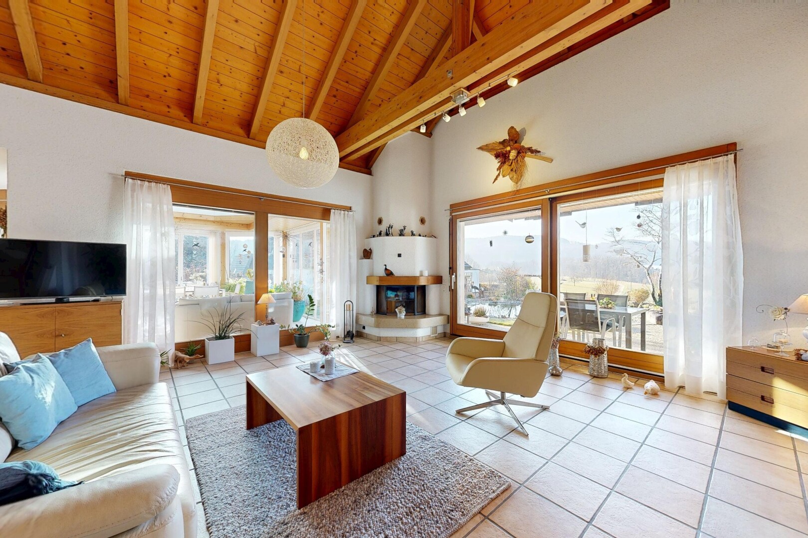 salon avec inside property, wood ceiling, plafond en bois, télévision, et high ceiling
