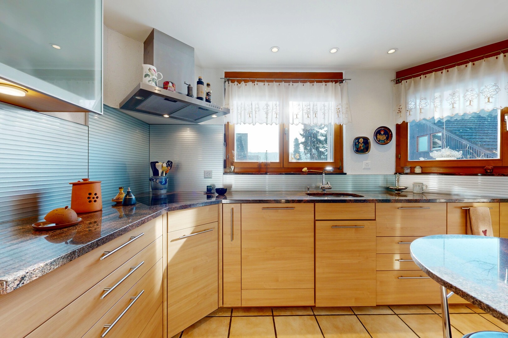 cuisine avec hotte, plans de travail en pierre, stone countertops, armoires à panneau plat, et flat panel cabinets