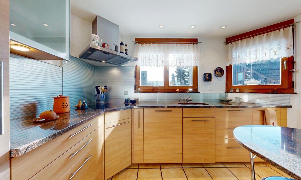 cuisine avec hotte, plans de travail en pierre, stone countertops, armoires à panneau plat, et flat panel cabinets