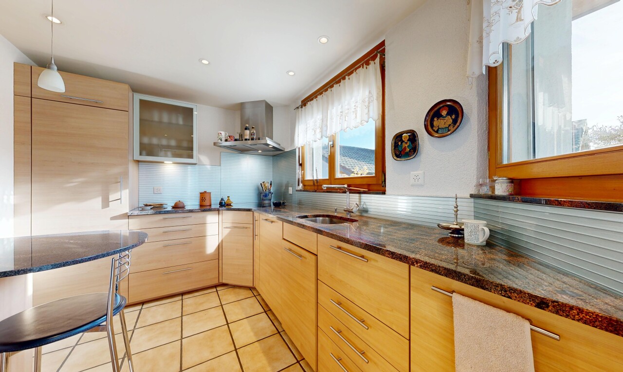 cuisine avec armoires marron clair, light brown cabinets, armoires avec insert en verre, glass insert cabinets, et dark countertops