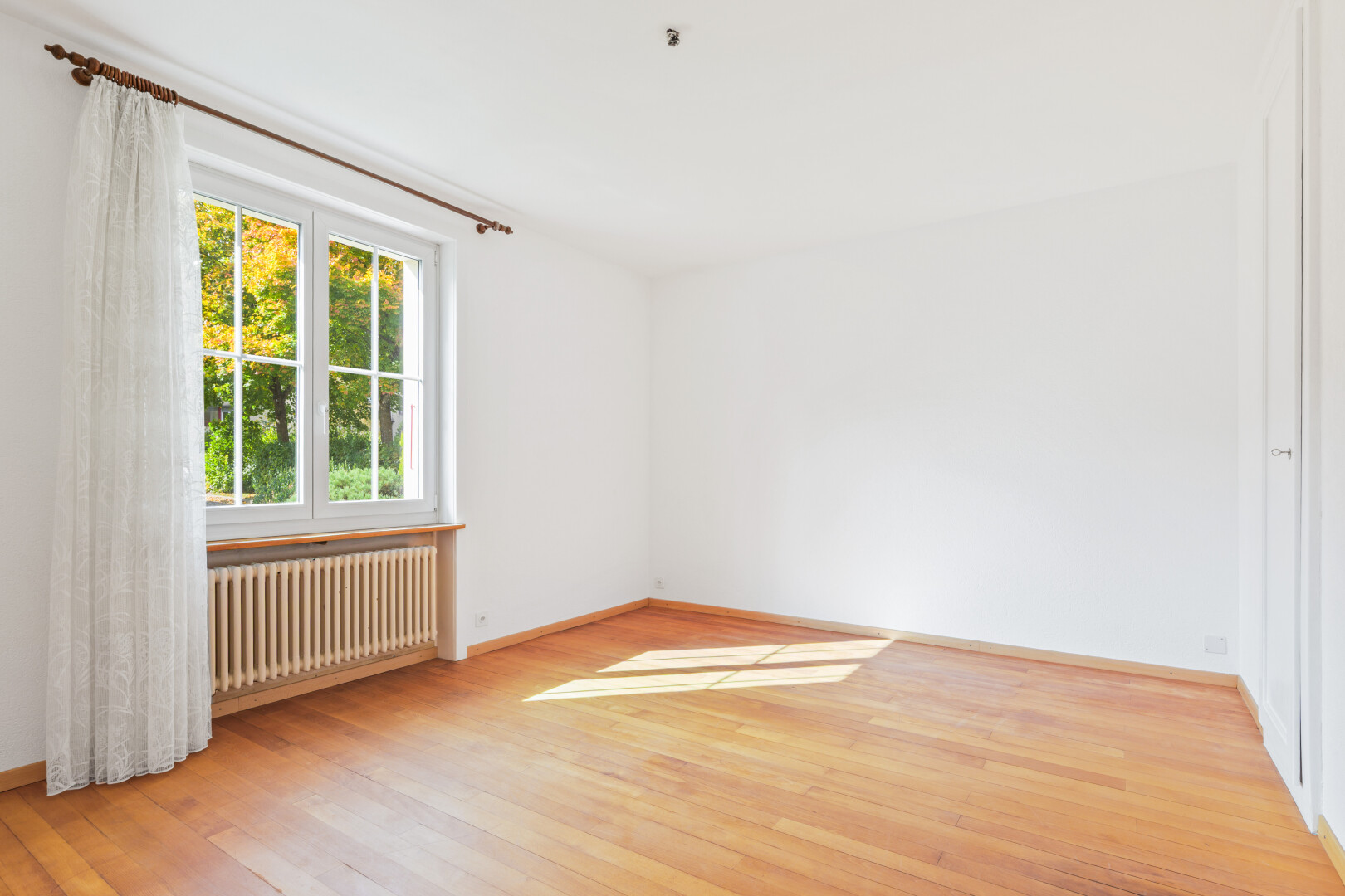 pièce vide avec natural light, lumière naturelle, radiateur, wood finish floor, et sol en finition bois