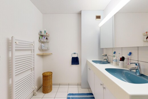 full bathroom featuring radiator, tasteful backsplash, double vanity, light tile patterned floors, and a towel warmer