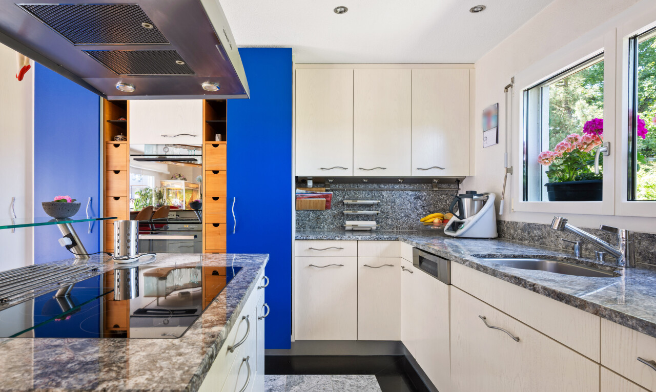 cuisine avec hotte, plans de travail en pierre, stone countertops, dark countertops, et dosseret