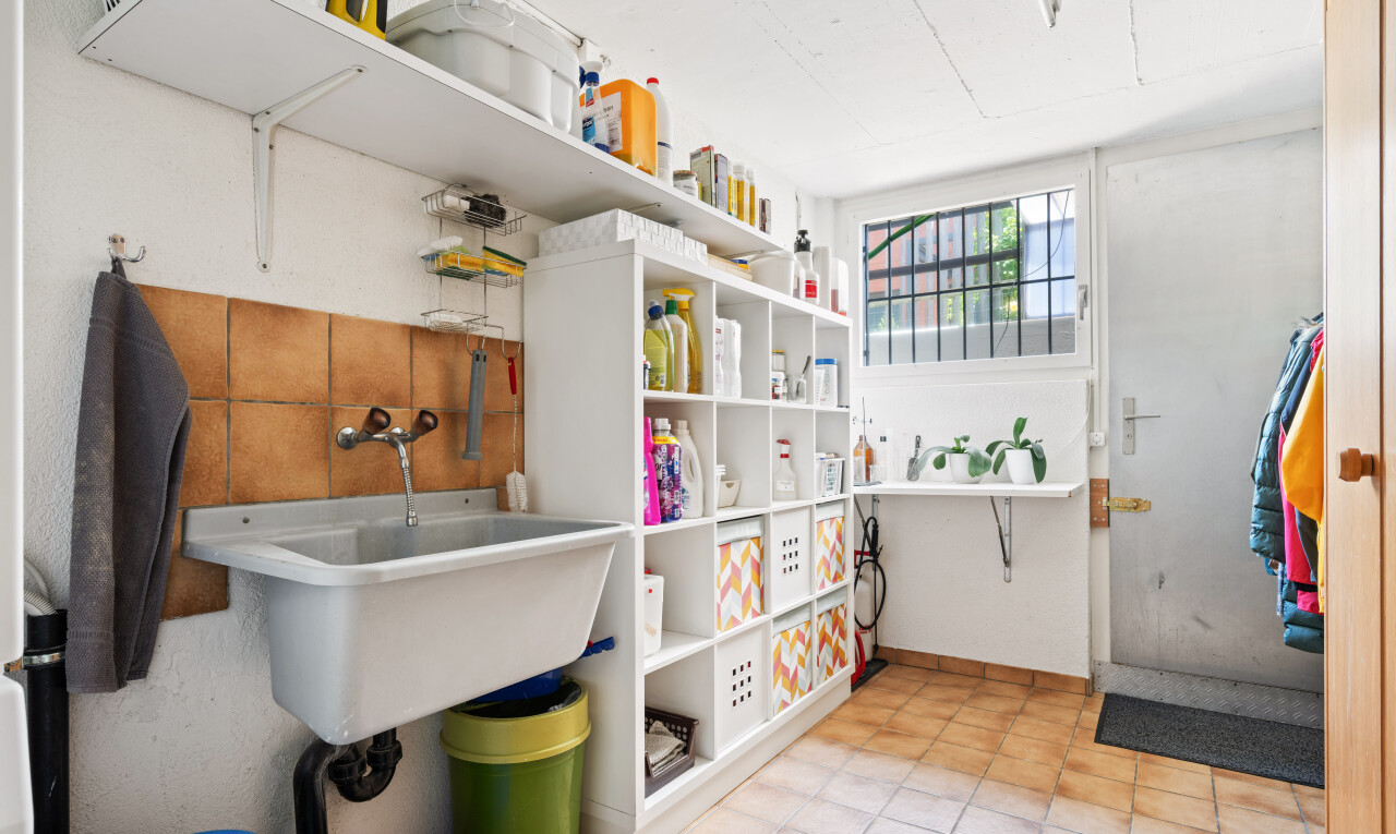 buanderie avec évier, lumière naturelle, light floor, drywall, et cloison sèche