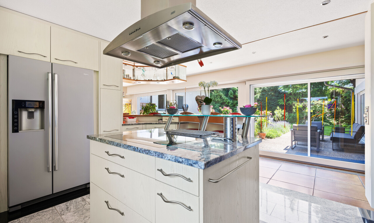 cuisine avec hotte, réfrigérateur, light floor, plans de travail en pierre, et stone countertops