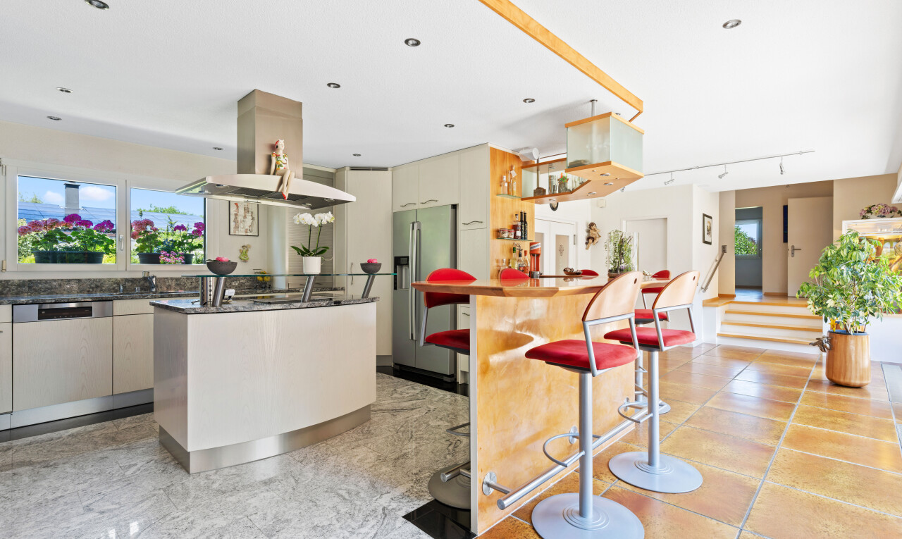 kitchen with island exhaust hood, high end refrigerator, a center island with sink, rail lighting, and a breakfast bar