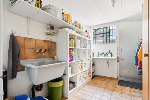 buanderie avec évier, lumière naturelle, light floor, drywall, et cloison sèche