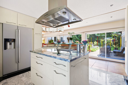 cuisine avec hotte, réfrigérateur, light floor, plans de travail en pierre, et stone countertops